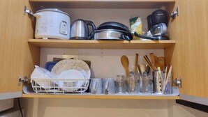 Un meuble de cuisine contenant des ustensiles de cuisine, des couverts et de la vaisselle.