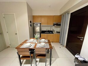 A compact kitchen with wooden cabinets, a built-in microwave, and a stainless steel refrigerator.