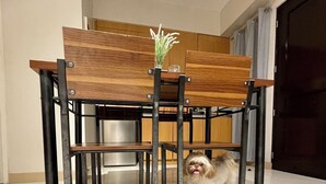 Un coin repas avec une table et des chaises en bois, une petite plante posée sur la table et deux chiens allongés sur le sol.