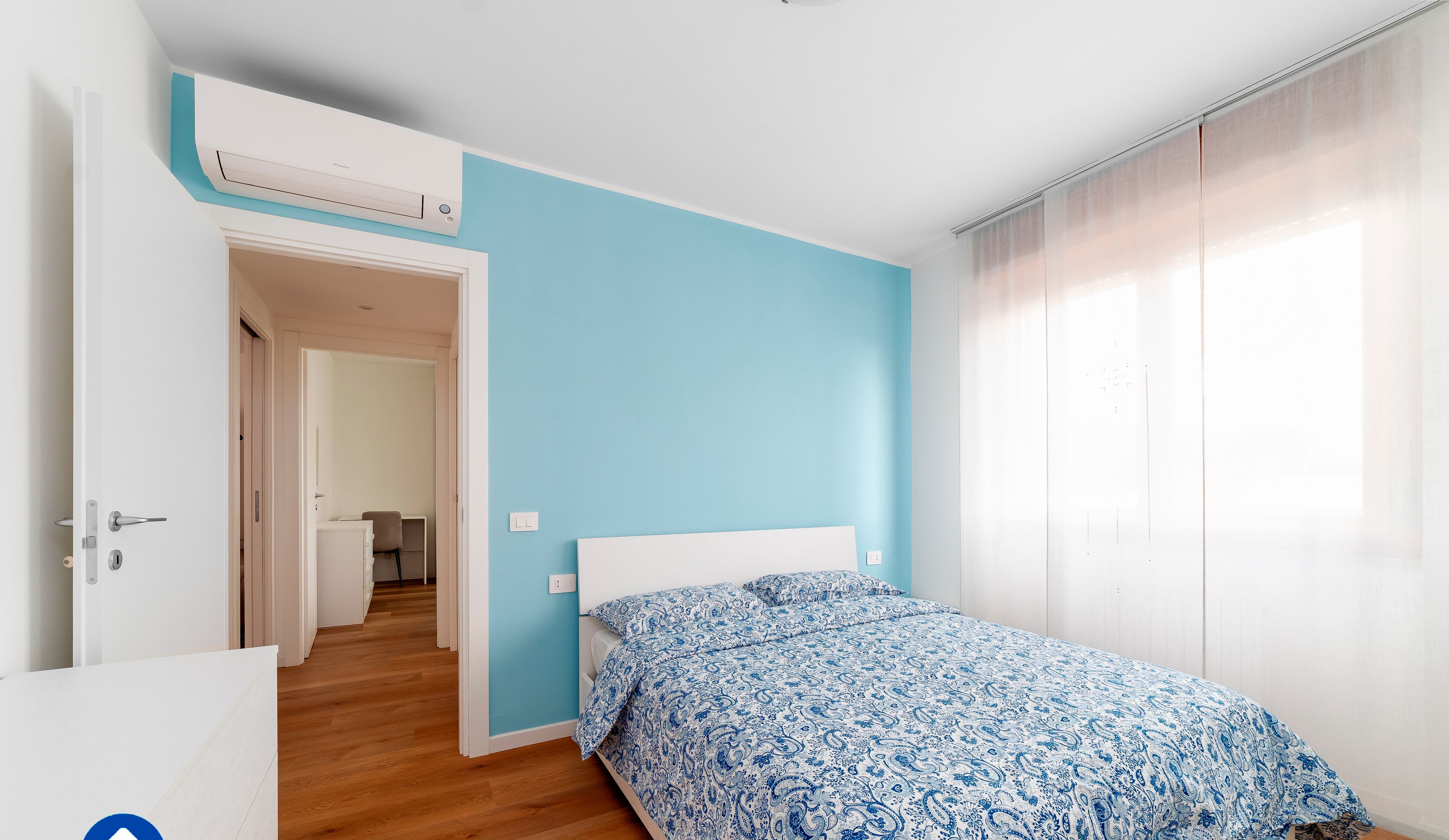 A bedroom with a bed, a wardrobe, and a door leading to another room.