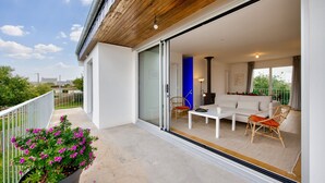 A modern outdoor living space with a white sofa, two chairs, a table, and a potted plant. - Sea view – House for 6 – 100 m from the beach (Plouguerneau)