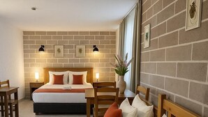 A hotel room with two beds, a wooden headboard, a brick wall, and a small table with a plant. - Q-Zen House Cunda (Ayvalik)
