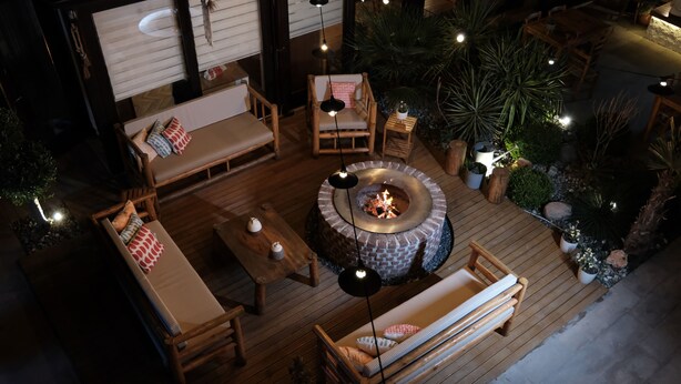 An outdoor patio with wooden furniture, a fire pit, and ambient lighting. - Q-Zen House Cunda (Ayvalik)