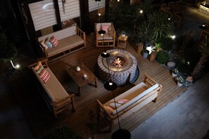 An outdoor patio with wooden furniture, a fire pit, and ambient lighting. - Q-Zen House Cunda (Ayvalik)
