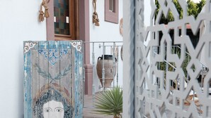 A courtyard with a decorative gate, a potted plant, and a wooden door with a painted design. - Q-Zen House Cunda (Ayvalik)