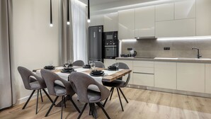 A modern kitchen with a dining area, featuring a wooden table, grey chairs, and contemporary appliances. - J&A Luxury Residence (Athens)