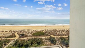 A beach view with a clear sky, sandy beach, and a fenced area with vegetation. - Includes Xplorie Activities & Linens. PYRAMID-2BR OFcondo w/outdoor pool. (Ocean City)