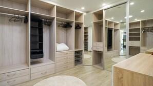 A modern walk-in closet with multiple storage compartments, a mirror, and a round rug on the floor. - Villa Luz de Maspalomas (Maspalomas)
