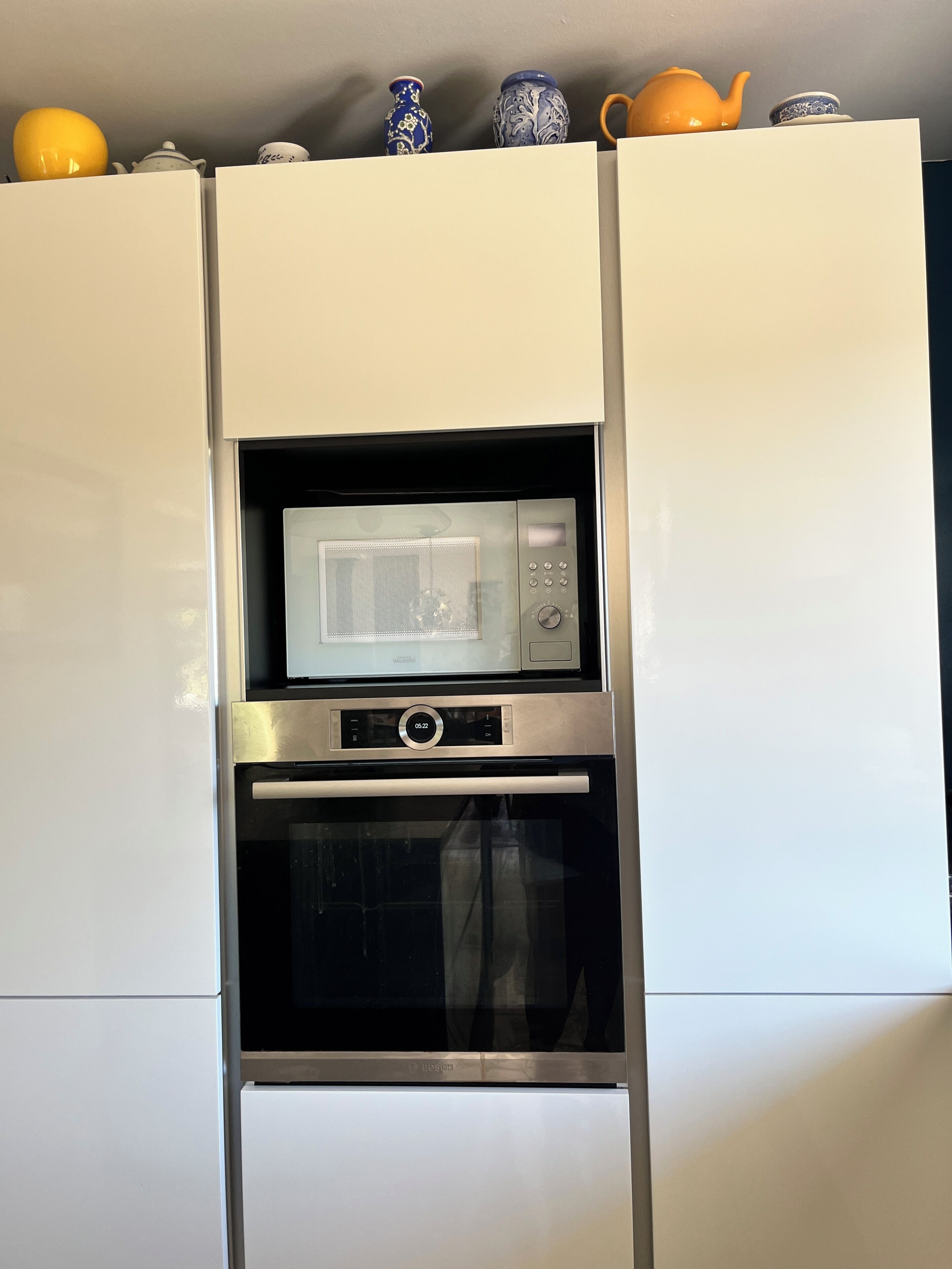 A kitchen with a microwave and oven built into a white cabinet.