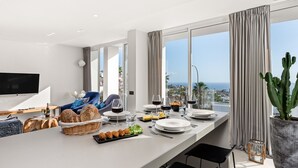 Een moderne keuken met een eethoek, grote ramen en uitzicht op zee.