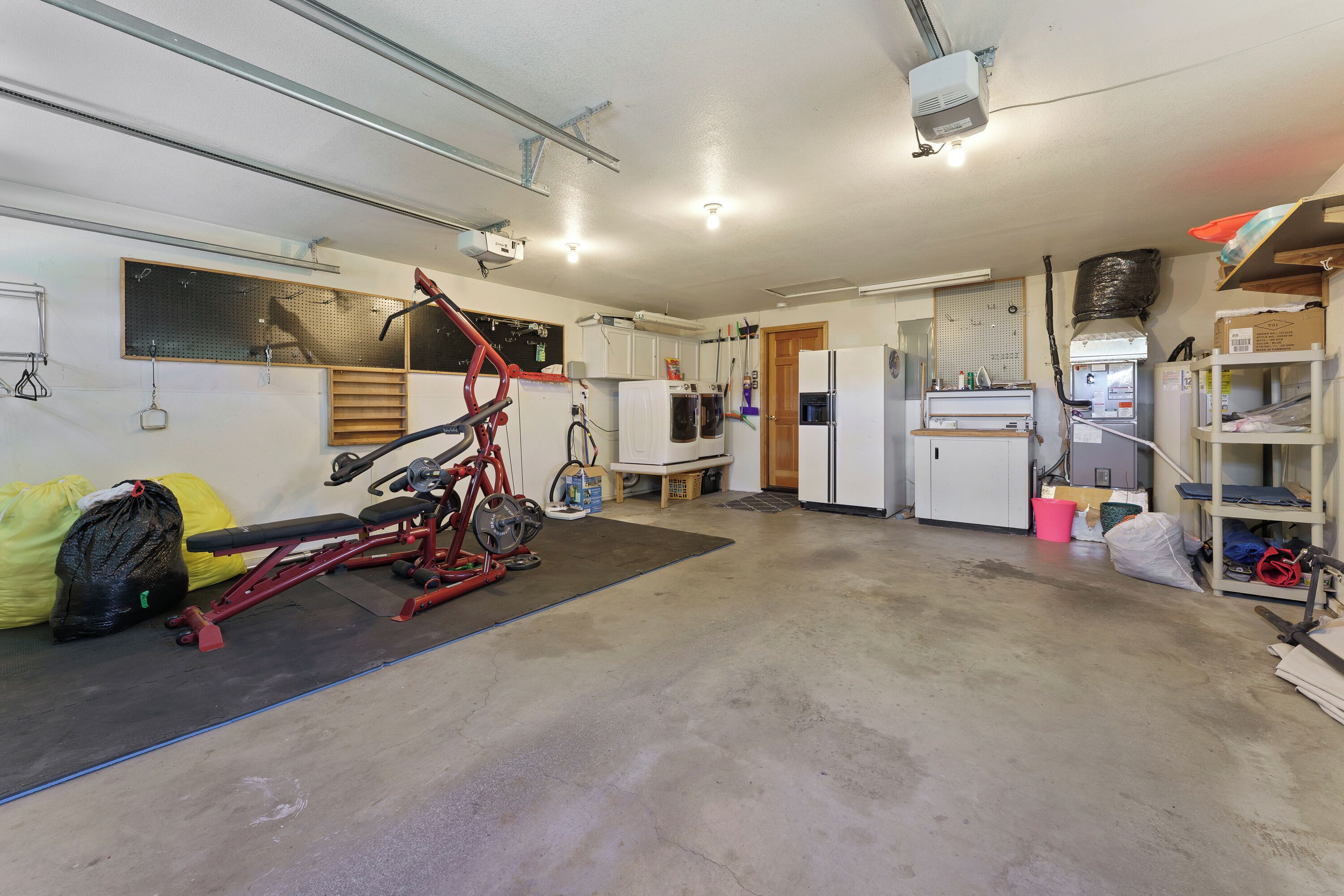 A garage with a red exercise bike, a refrigerator, and various storage items.