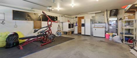 A garage with a red exercise bike, a refrigerator, and various storage items.