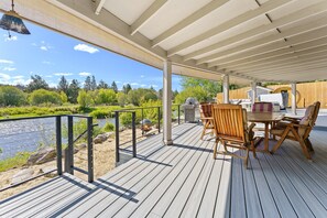 Enjoy a serene river view from this outdoor deck with a grill, seating area, and riverbank access.
