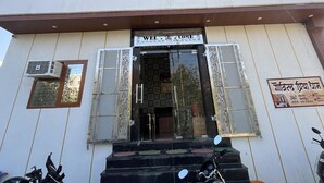 Un edificio de varios pisos con un letrero que dice "WELCOME", una escalera que conduce a la entrada y dos motocicletas estacionadas frente.
