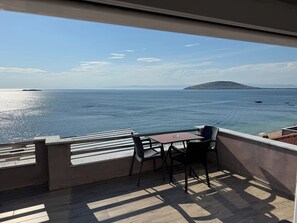 A balcony with a table and chairs, overlooking a body of water with boats and a distant island. - Patama Butik Otel (Marmara)