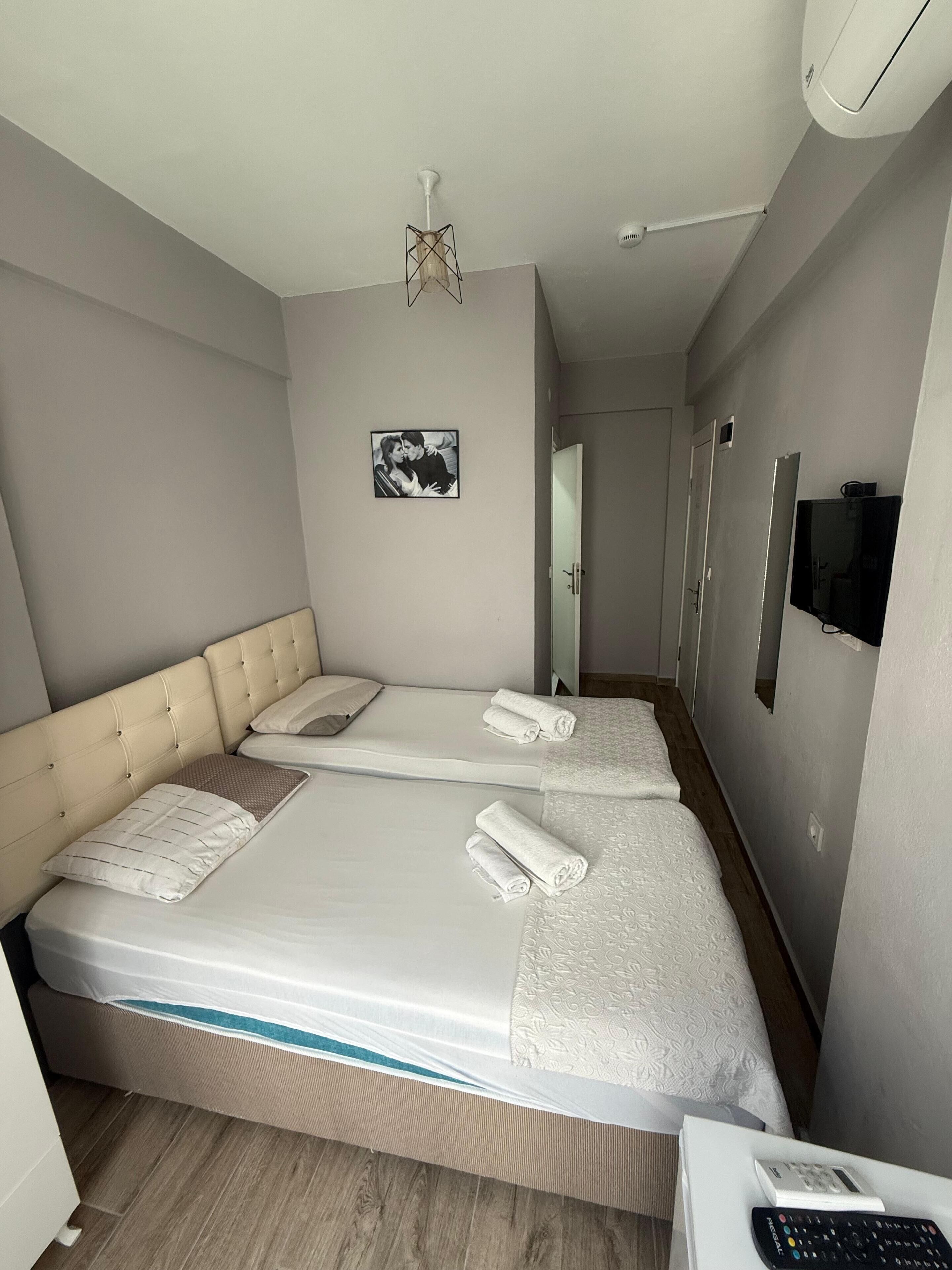 Een hotelkamer met twee bedden, een televisie en een schilderij aan de muur.