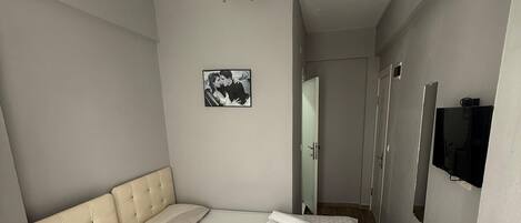 A hotel room with two beds, a television, and a picture on the wall.