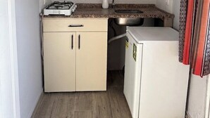 Une cuisine de taille réduite, équipée d’une cuisinière à gaz, d’un évier et d’un petit réfrigérateur.