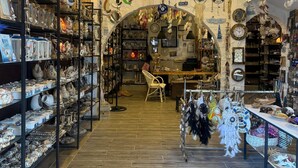 Un magasin où l’on trouve des étagères remplies d’objets décoratifs, un espace central aménagé avec des sièges et un plafond orné de décorations suspendues.
