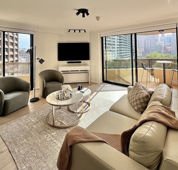 Una sala de estar moderna con un sofá, sillones, una mesa de centro y un televisor.