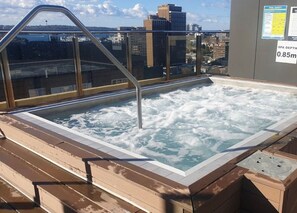 A rooftop hot tub with a view of the city skyline.