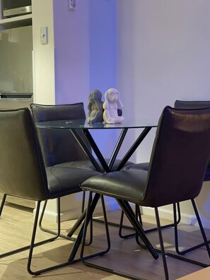 A dining area with a glass table and four black chairs. - Elegant Hyde Park View Retreat with Rooftop Spa Sauna Pool and Gym (Darlinghurst)