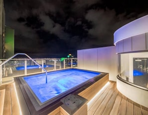 A rooftop pool with a glass balustrade, a hot tub, and a city view at night. - Elegant Hyde Park View Retreat with Rooftop Spa Sauna Pool and Gym (Darlinghurst)