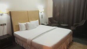 Una habitación de hotel con una cama grande, una mesita de noche, una silla y una pequeña mesa.