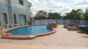 Una piscina con cubierta de baldosas, sillas de descanso y un flotador.