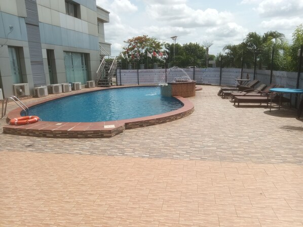 A swimming pool with a tiled deck, lounge chairs, and a lifebuoy. - golden tulip essential (Owerri)
