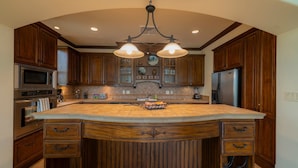 Un'ampia cucina con un'isola grande, mobili in legno, elettrodomestici in acciaio inossidabile e un elegante lampadario.