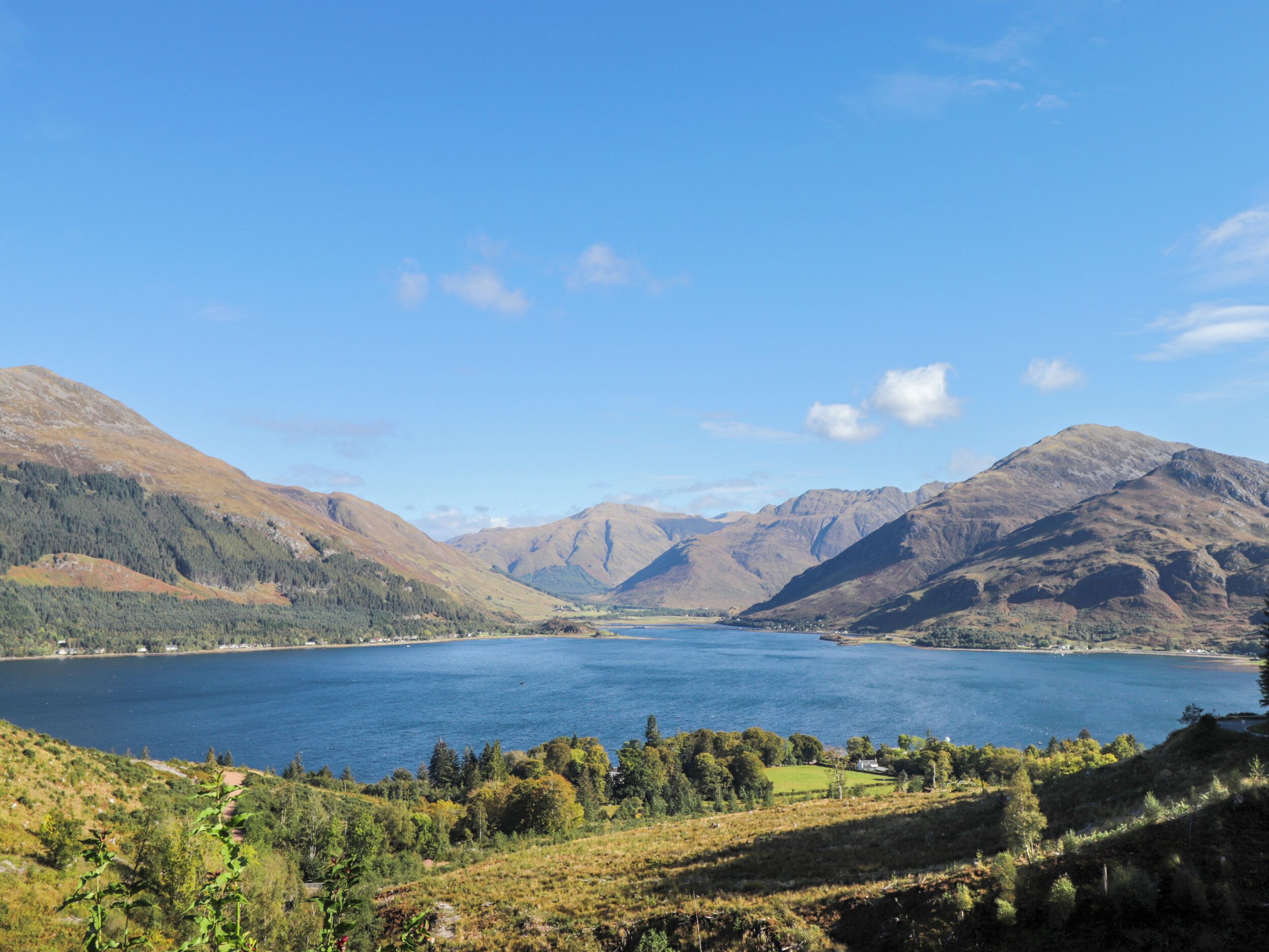 Vista panorámica de un lago rodeado de montañas, con cielo despejado y sin edificios ni personas a la vista.