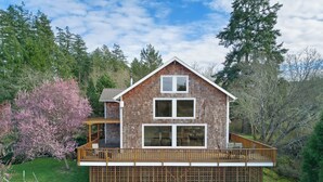 A two-story house with a wooden deck and a large window. - Island Escape with Comfort and Privacy -Margo House (Friday Harbor)