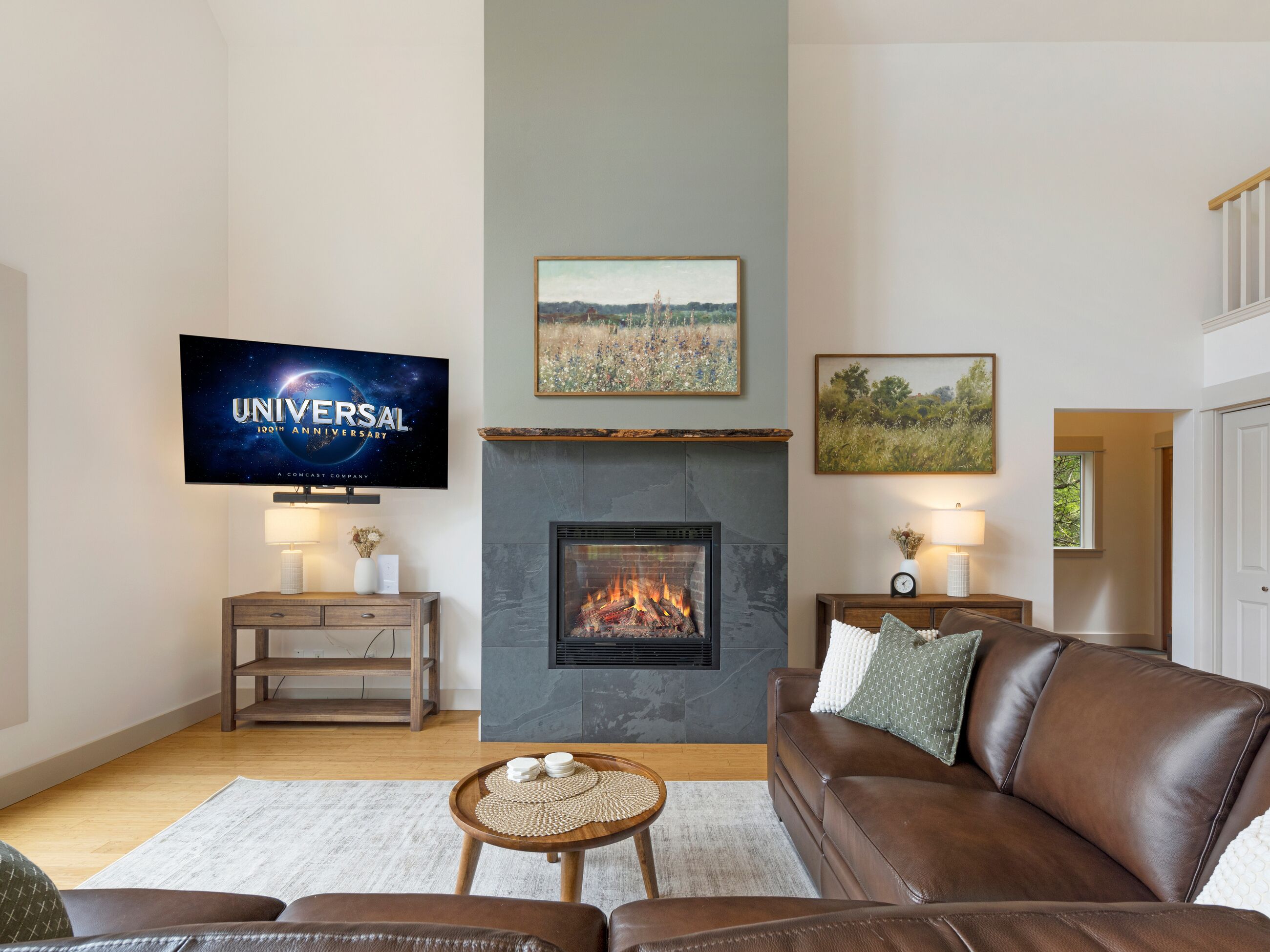 A living room with a fireplace, a television, and two paintings on the wall.