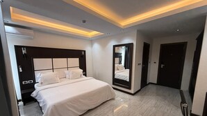 A modern hotel room with a large bed, a built-in mirror, and recessed lighting.