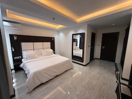 Una habitación de hotel moderna con una cama grande, un espejo integrado e iluminación empotrada.