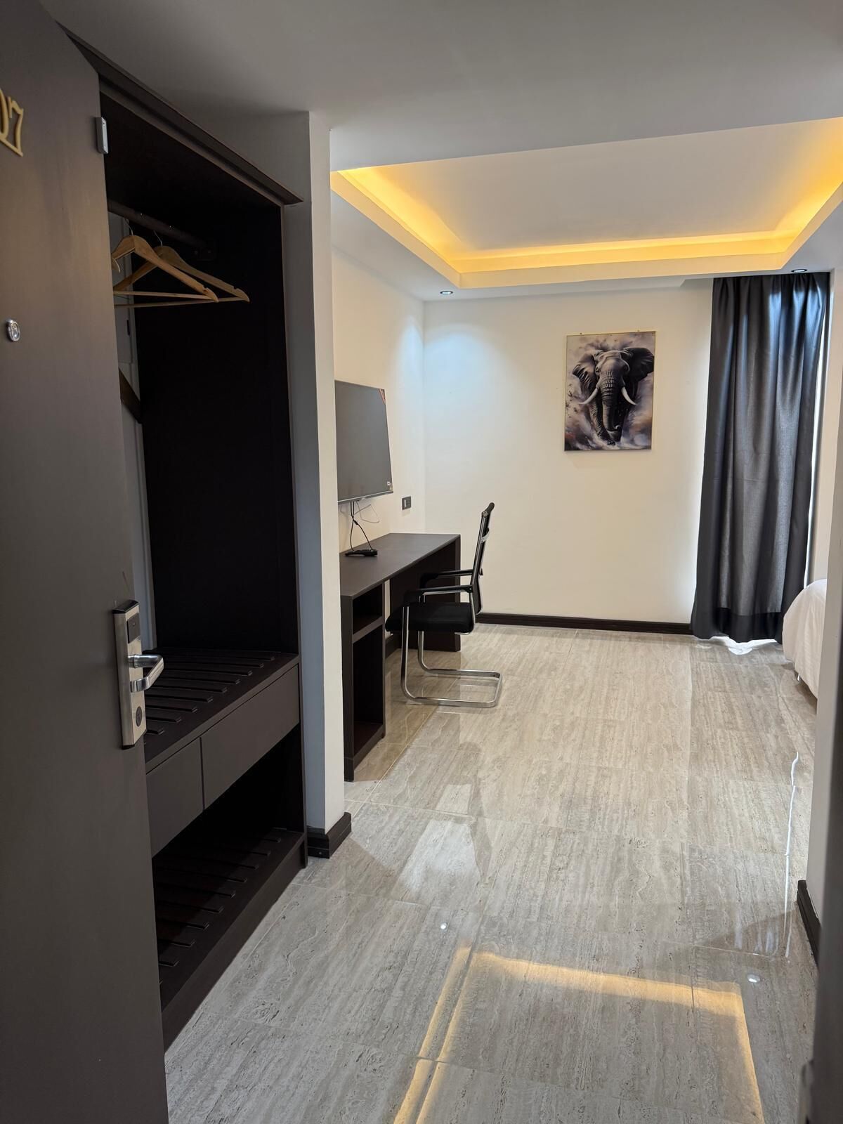Une chambre d’hôtel moderne, équipée d’un lit, d’un bureau, d’une chaise, d’une télévision et d’un tableau au mur.