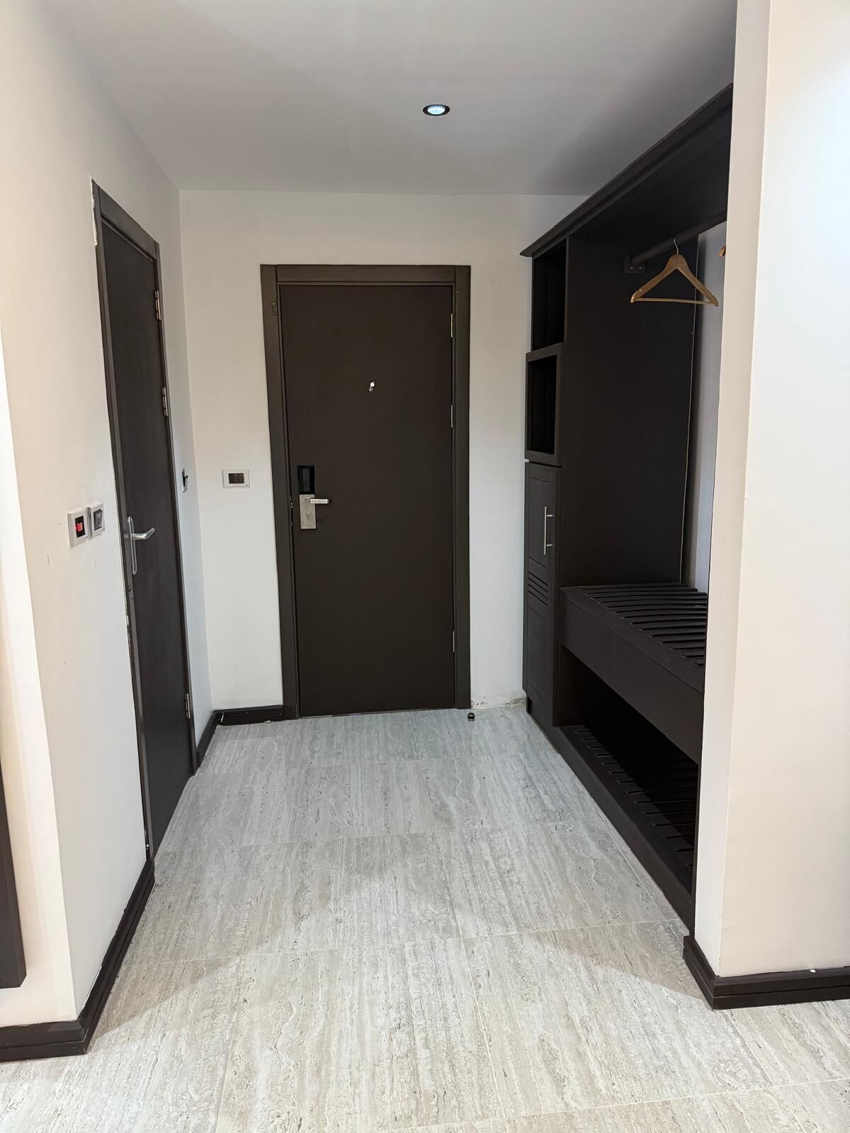 A hallway with a dark door, a coat rack, and a built-in bench.