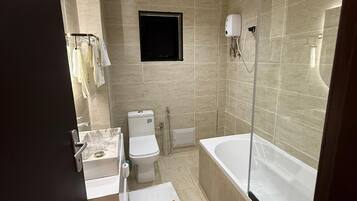 A modern bathroom with a toilet, bidet, and bathtub.