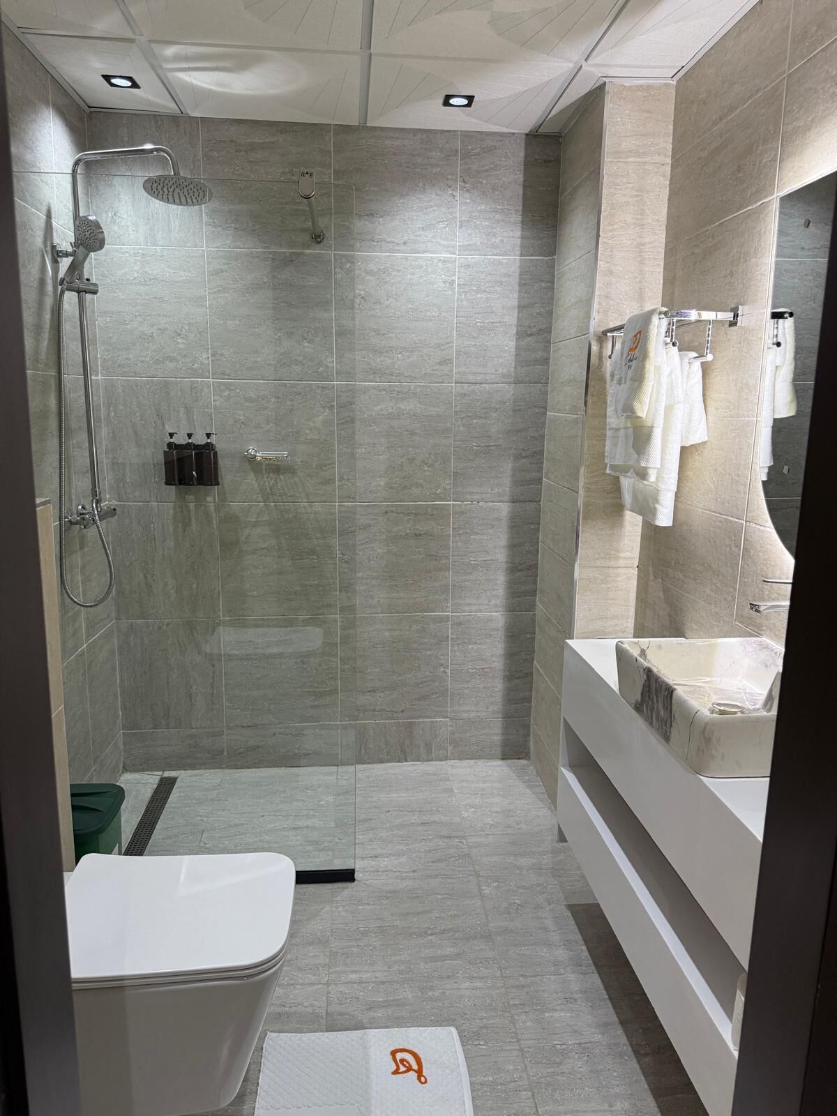 Un baño moderno con cabina de ducha, inodoro y tocador con lavabo.