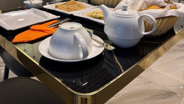 A breakfast setting with a marble table, white teapot, and various breakfast items.