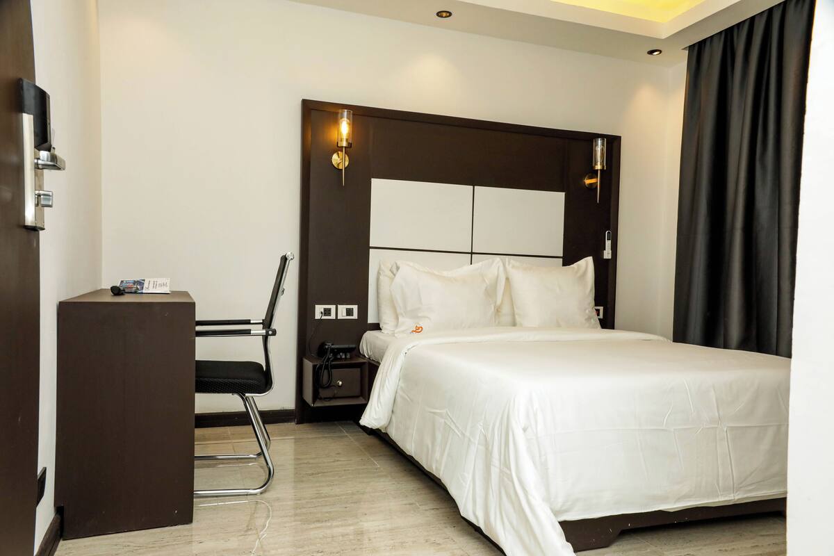 A hotel room with a bed, a desk, and a chair.