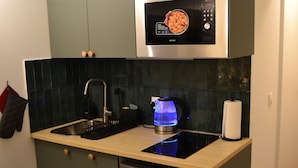 A compact kitchen with a microwave, kettle, and dishwasher.