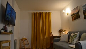 A living room with a television, a sofa, a small table, and a chair.