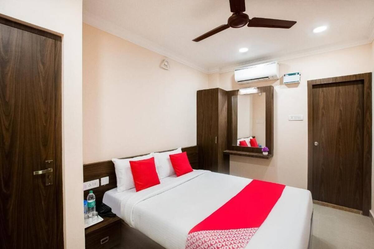 Una habitación de hotel con cama, mesita de noche, espejo y ventilador de techo.