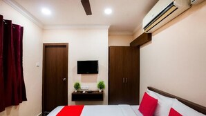 Ein Hotelzimmer mit Bett, Wandfernseher, Kleiderschrank und Klimaanlage.