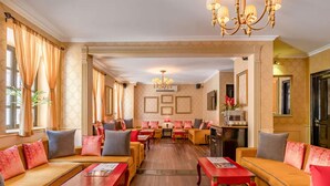 A spacious hotel lobby with multiple seating areas, a chandelier, and framed artwork on the walls. - La Maison by Dia Hotels and Homes (Panaji)