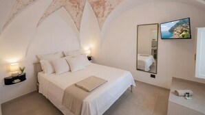 A bedroom with a bed, bedside lamps, a TV, a mirror, and a view of the sea. - Le Camere sul Golfo (Gallipoli)
