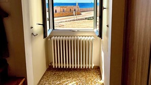 A room with a large window overlooking a beach and a clear blue sky. - Le Camere sul Golfo (Gallipoli)