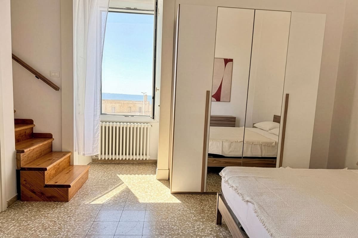 A bedroom with a bed, a wardrobe, a window, and a staircase.